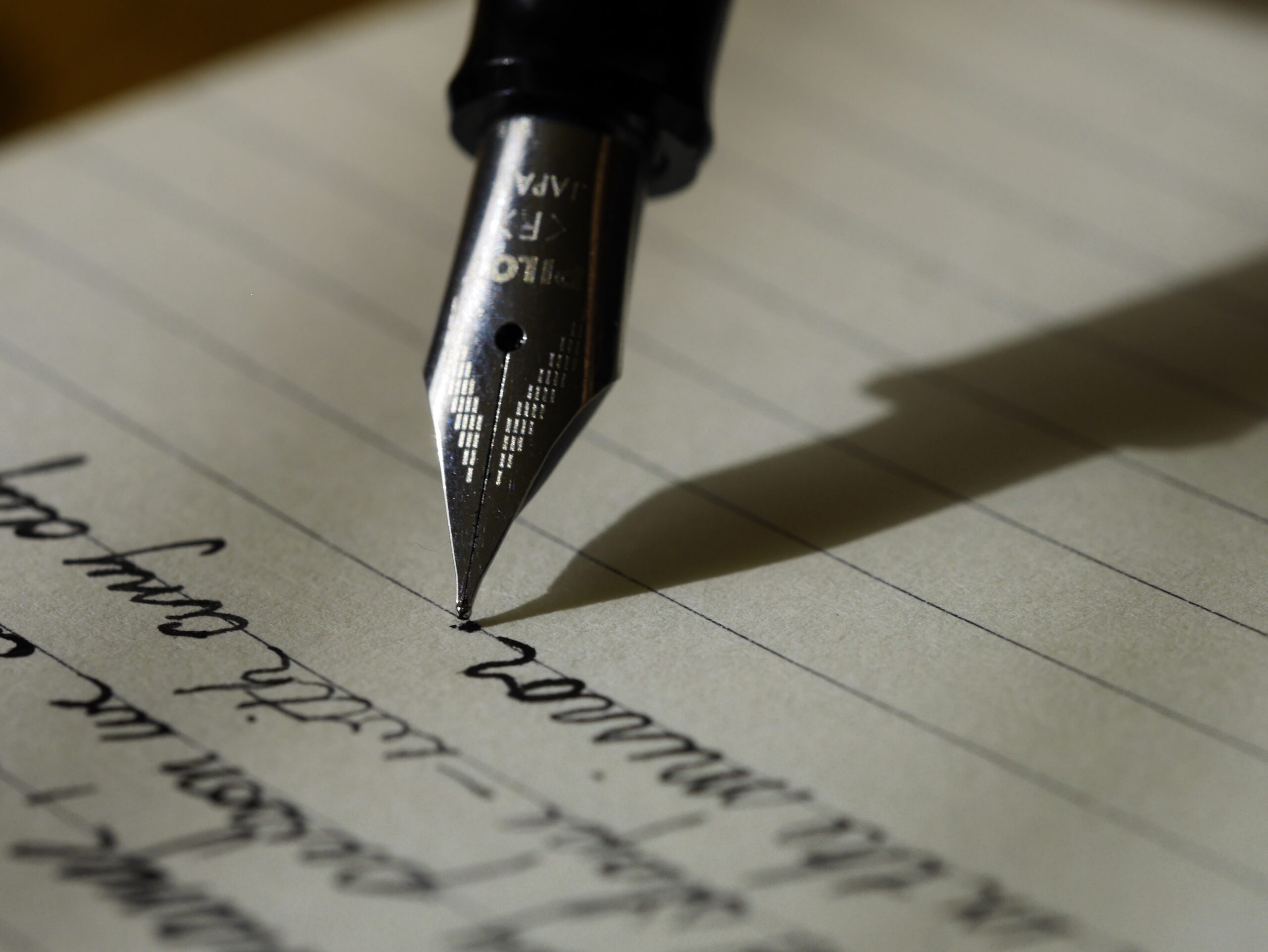 A fountain pen writing in cursive on a piece of paper