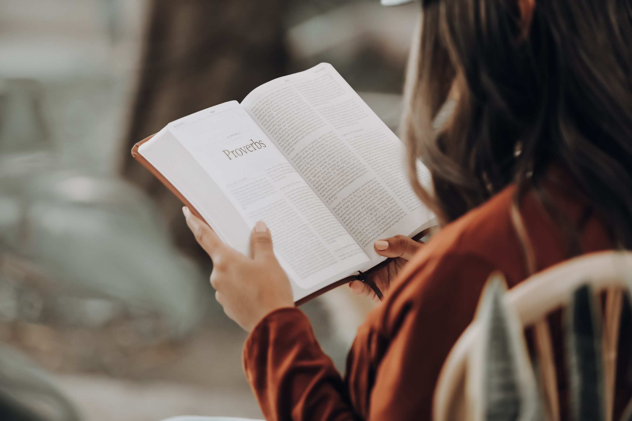 Girl carefully reading a book while siting down.