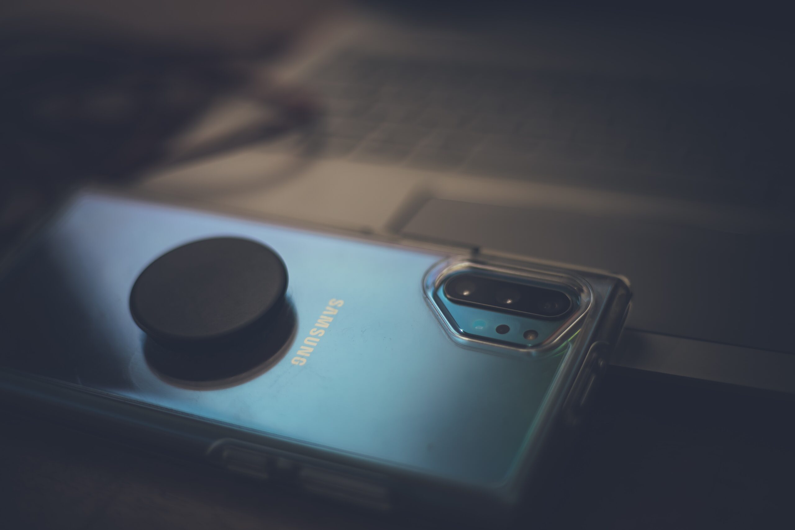 Mobile phone facing down on a counter top, dimly lit and with a blurred background.