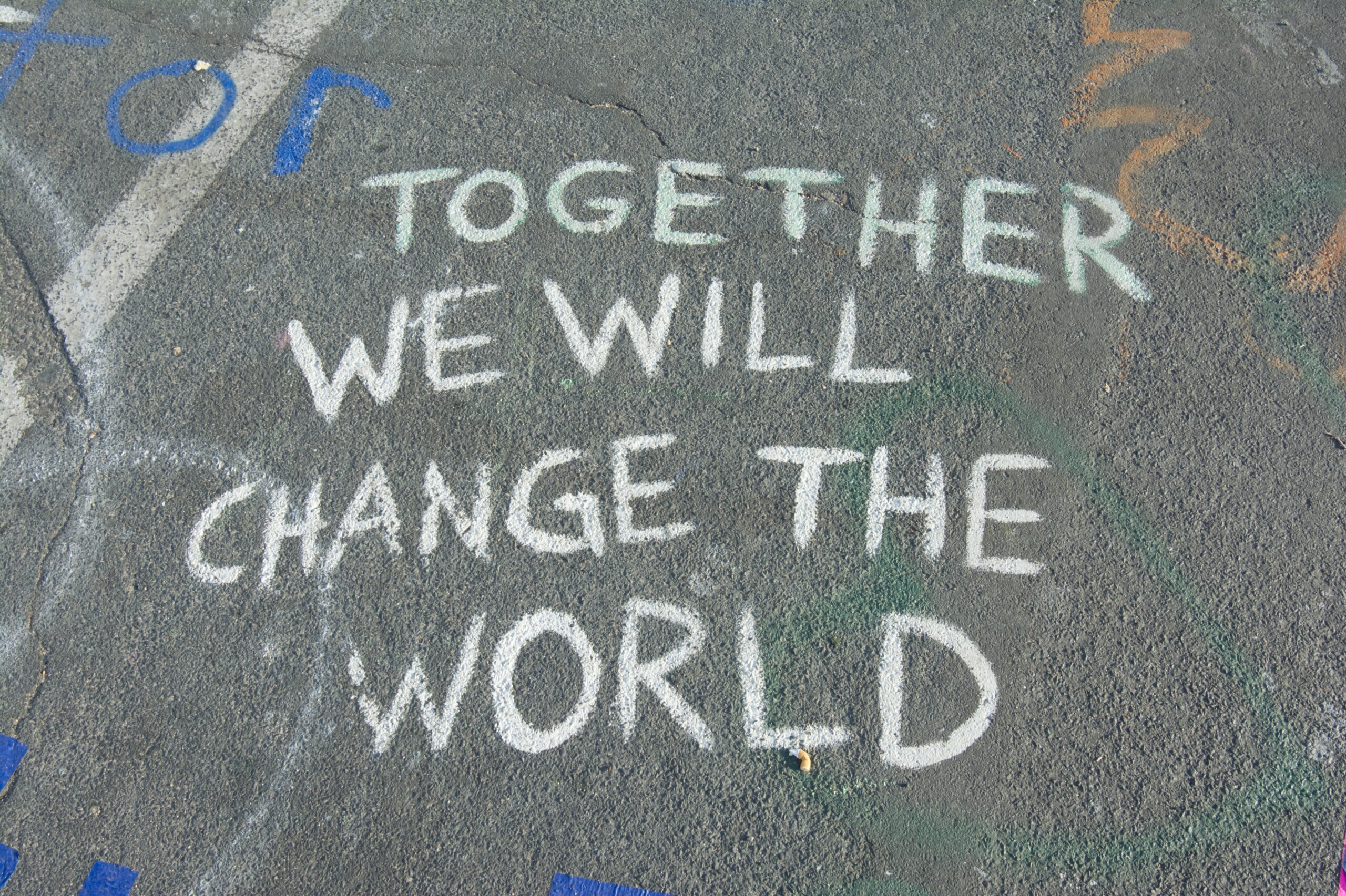 Chalk on the road that reads "together we will change the world"